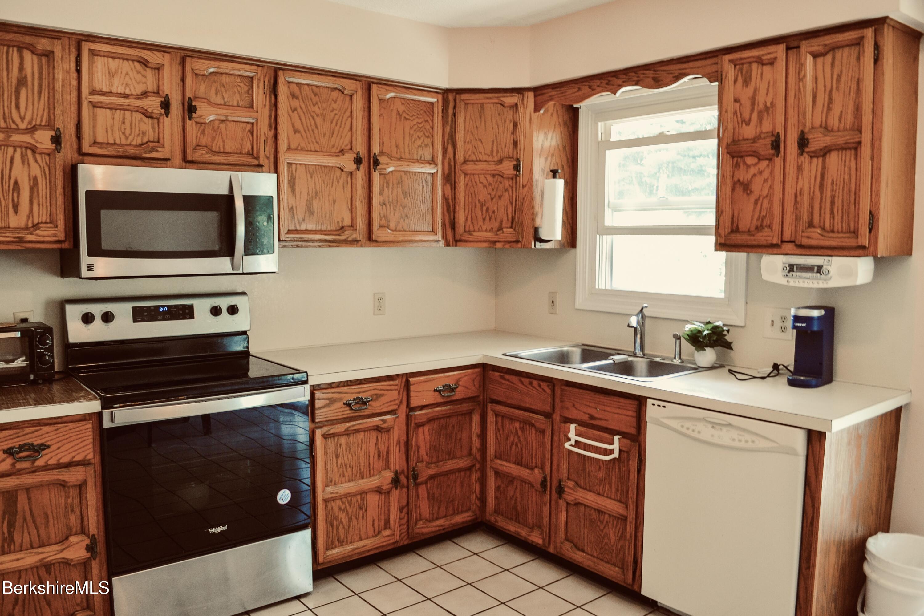 127 Oak Hill Road Pittsfield, MA 01201 - Photo 8 of 22 a kitchen with stainless steel appliances granite countertop a sink dishwasher stove and microwave with wooden cabinets