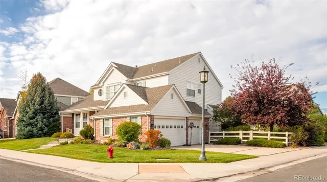 a view of a white house next to a yard with large trees
