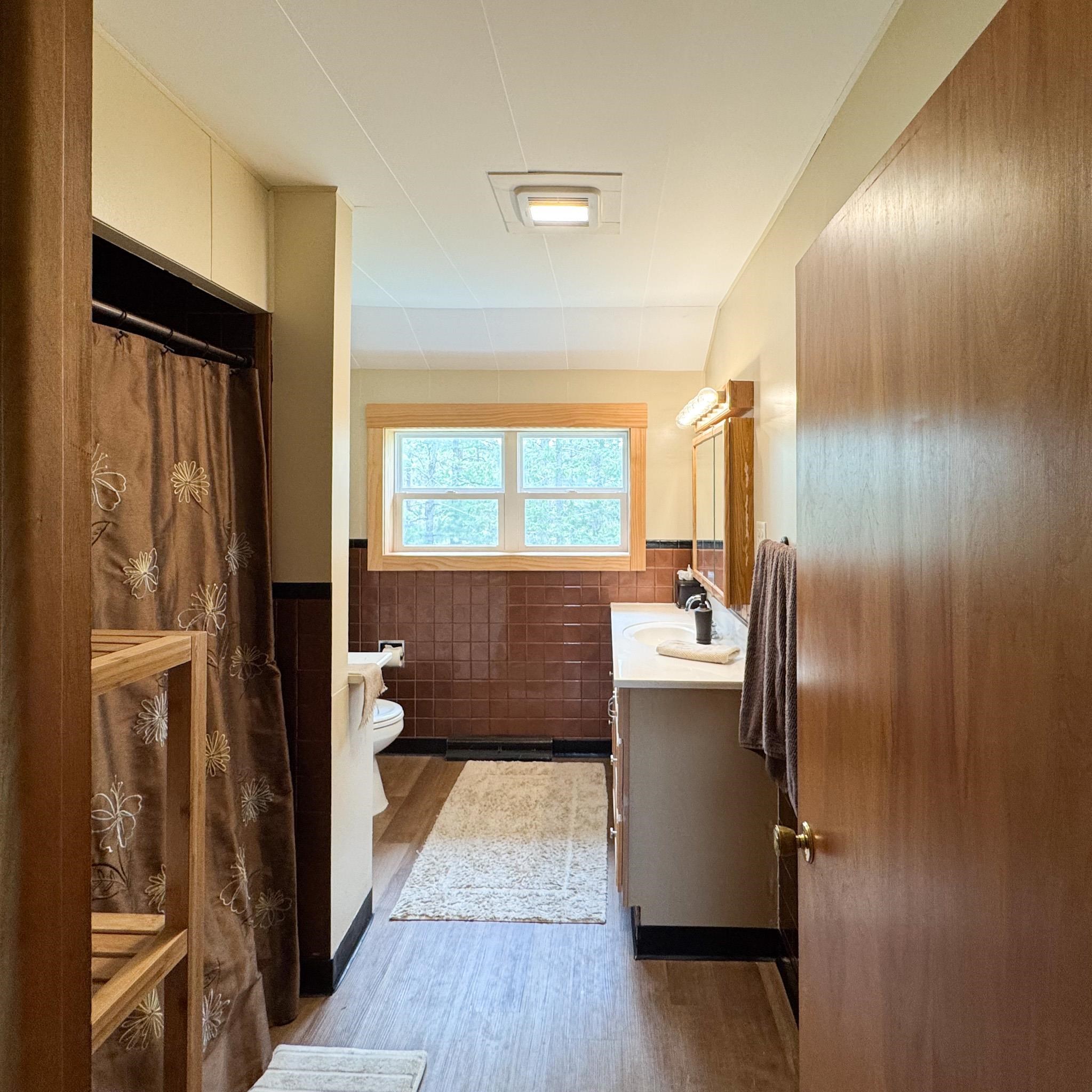 201 Golf Course Lane Bigfork, MN 56628 - Photo 8 of 30 Full bathroom with a wainscoted wall, tile walls, vanity, toilet, and wood finished floors