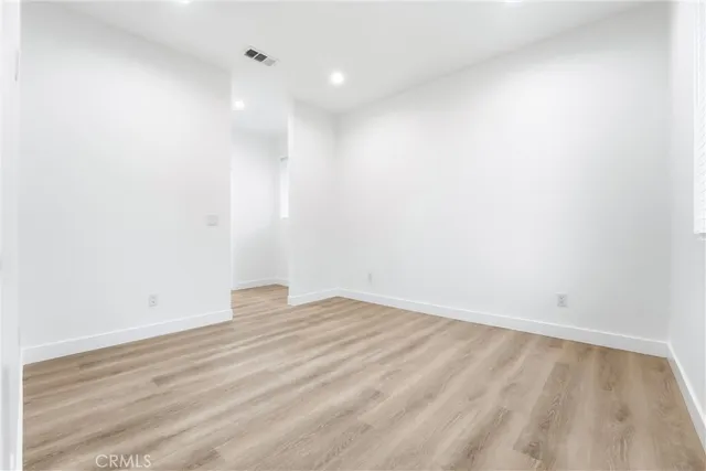 a large white kitchen with stainless steel appliances granite countertop a stove a sink a refrigerator and white cabinets with wooden floor