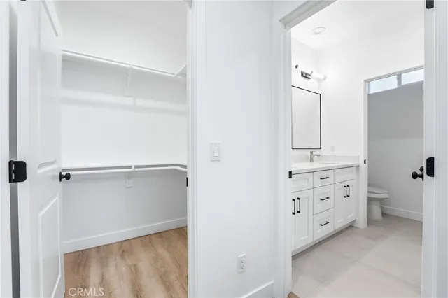 a kitchen with stainless steel appliances kitchen island granite countertop a refrigerator a stove oven a sink dishwasher and white cabinets with wooden floor