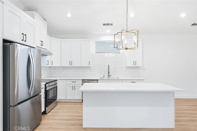 a large white kitchen with wooden floor and stainless steel appliances