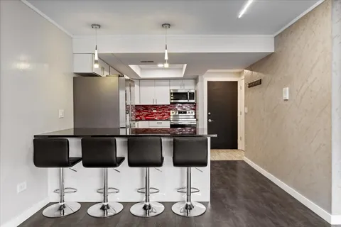 a kitchen with stainless steel appliances kitchen island granite countertop a dining table chairs and granite counter tops