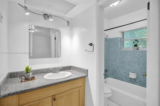a bathroom with a granite countertop sink a toilet a mirror a vanity and shower