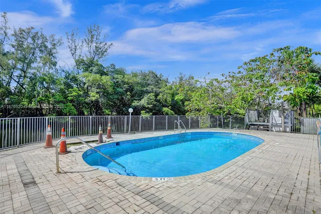 a view of swimming pool with seating space and trees in the background