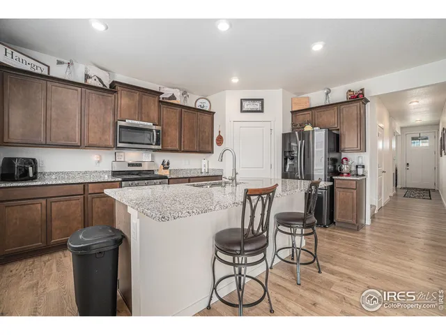 a kitchen with granite countertop a refrigerator and a stove top oven