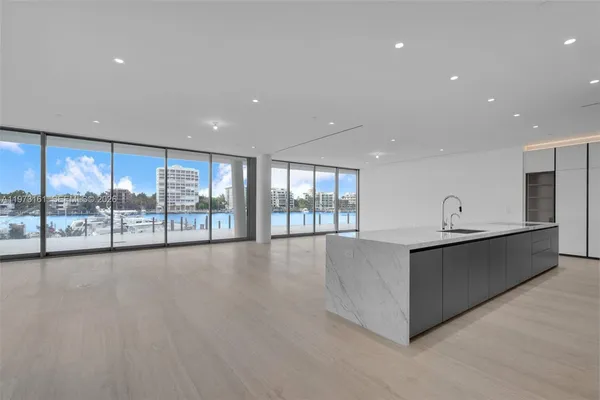 a large hall with stainless steel appliances granite countertop a large counter top and a wooden floors