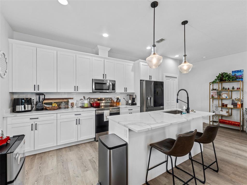 3103 West Leroy Street Tampa, FL 33607 - Photo 8 of 29 a open kitchen with stainless steel appliances granite countertop a stove a sink dishwasher and a dining table with wooden floor