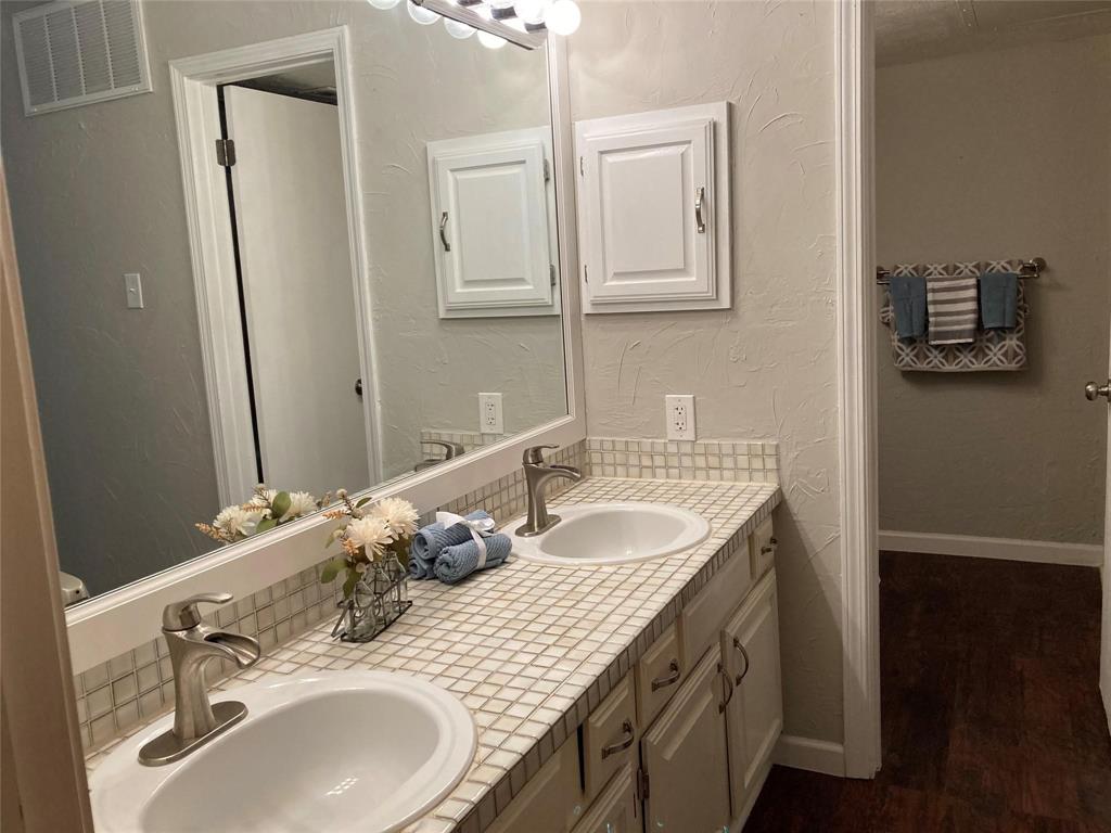 18240 Midway Road, Unit 905 Dallas, TX 75287 - Photo 10 of 15 Full bathroom with a textured wall, double vanity, and dark wood-style flooring