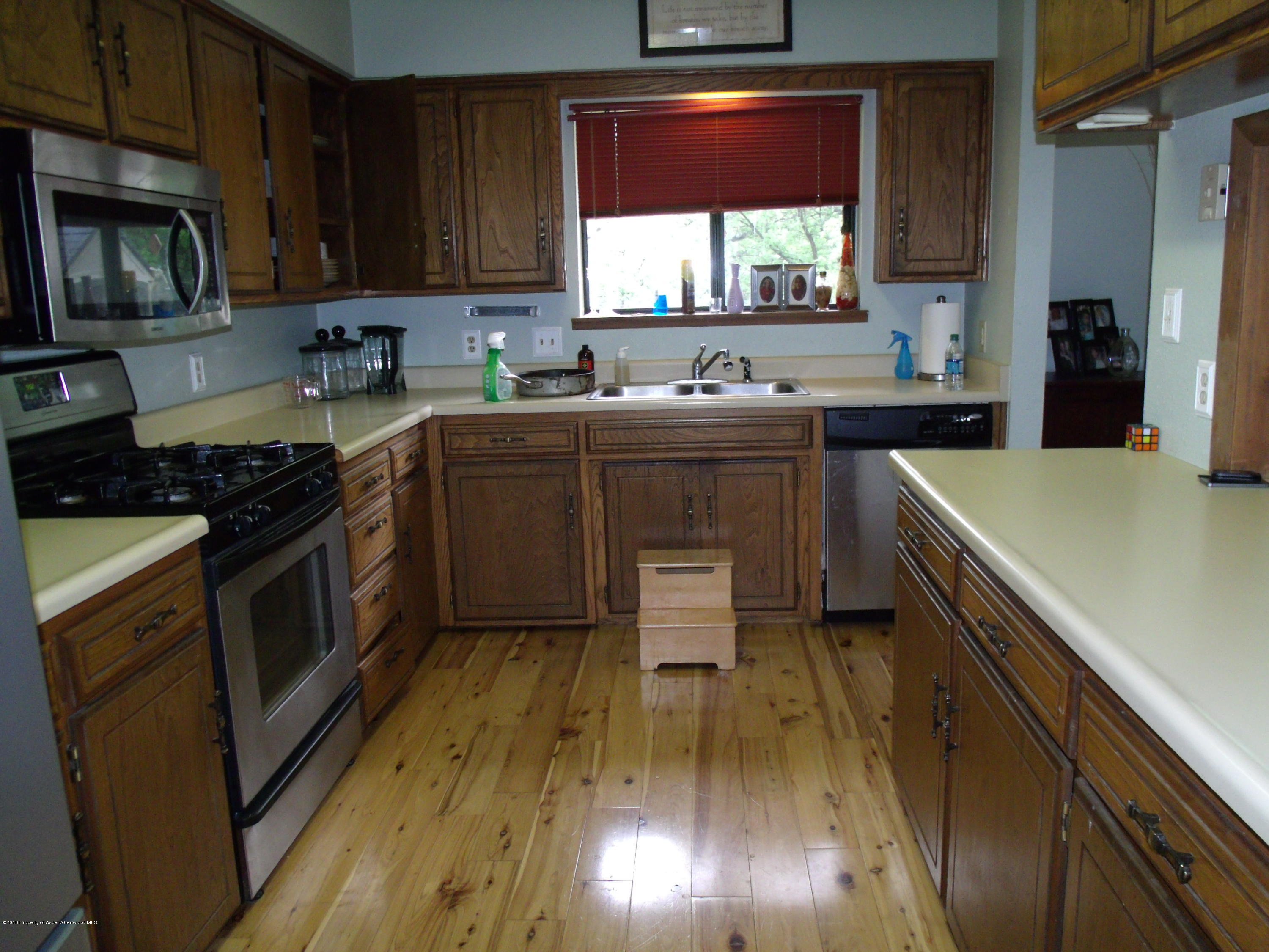 610 Ash Avenue Rifle, CO 81650 - Photo 12 of 18 a kitchen with stainless steel appliances a stove a sink a microwave and wooden cabinets