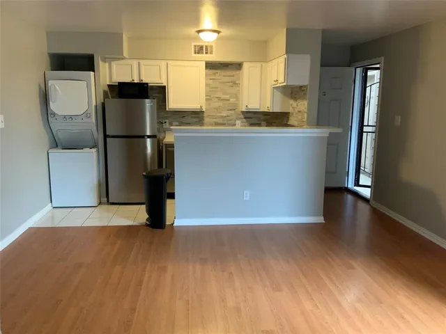 a kitchen with stainless steel appliances a refrigerator and a hard wood floor