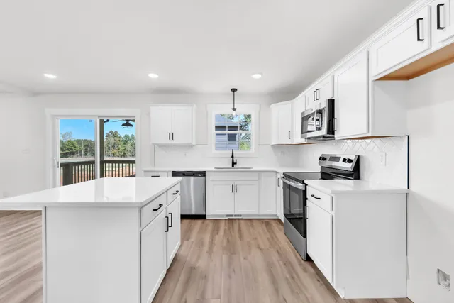 a kitchen with a sink a stove a refrigerator and white cabinets