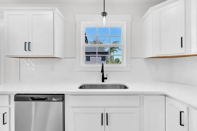 a kitchen with stainless steel appliances granite countertop a sink a stove and a refrigerator with white cabinets