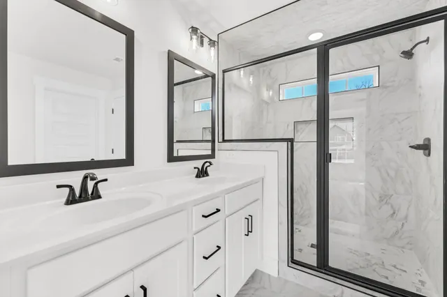a bathroom with a double vanity sink mirror and shower