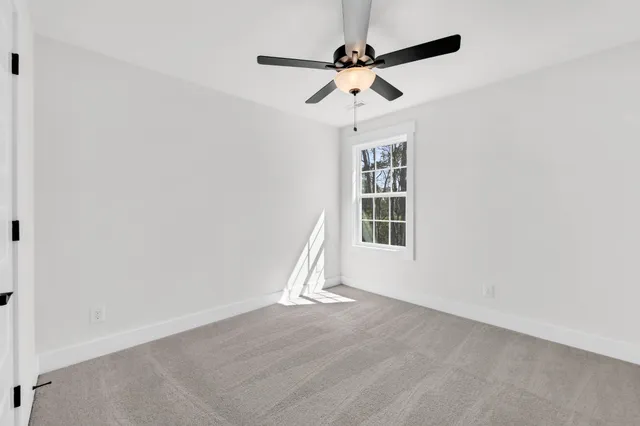 an empty room with wooden floor ceiling fan and windows