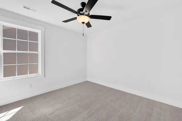 an empty room with a window and a fan