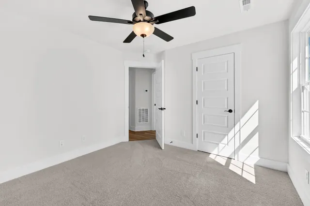 an empty room with a window and a ceiling fan