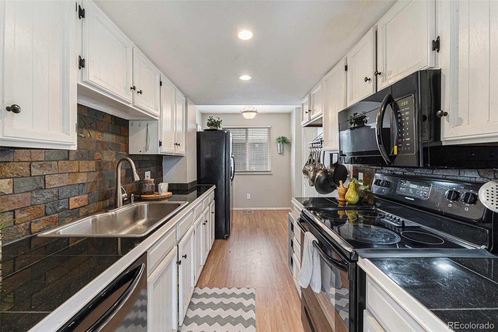 8642 Carr Loop Arvada, CO 80005 - Photo 2 of 22 a kitchen with stainless steel appliances a sink stove microwave and cabinets