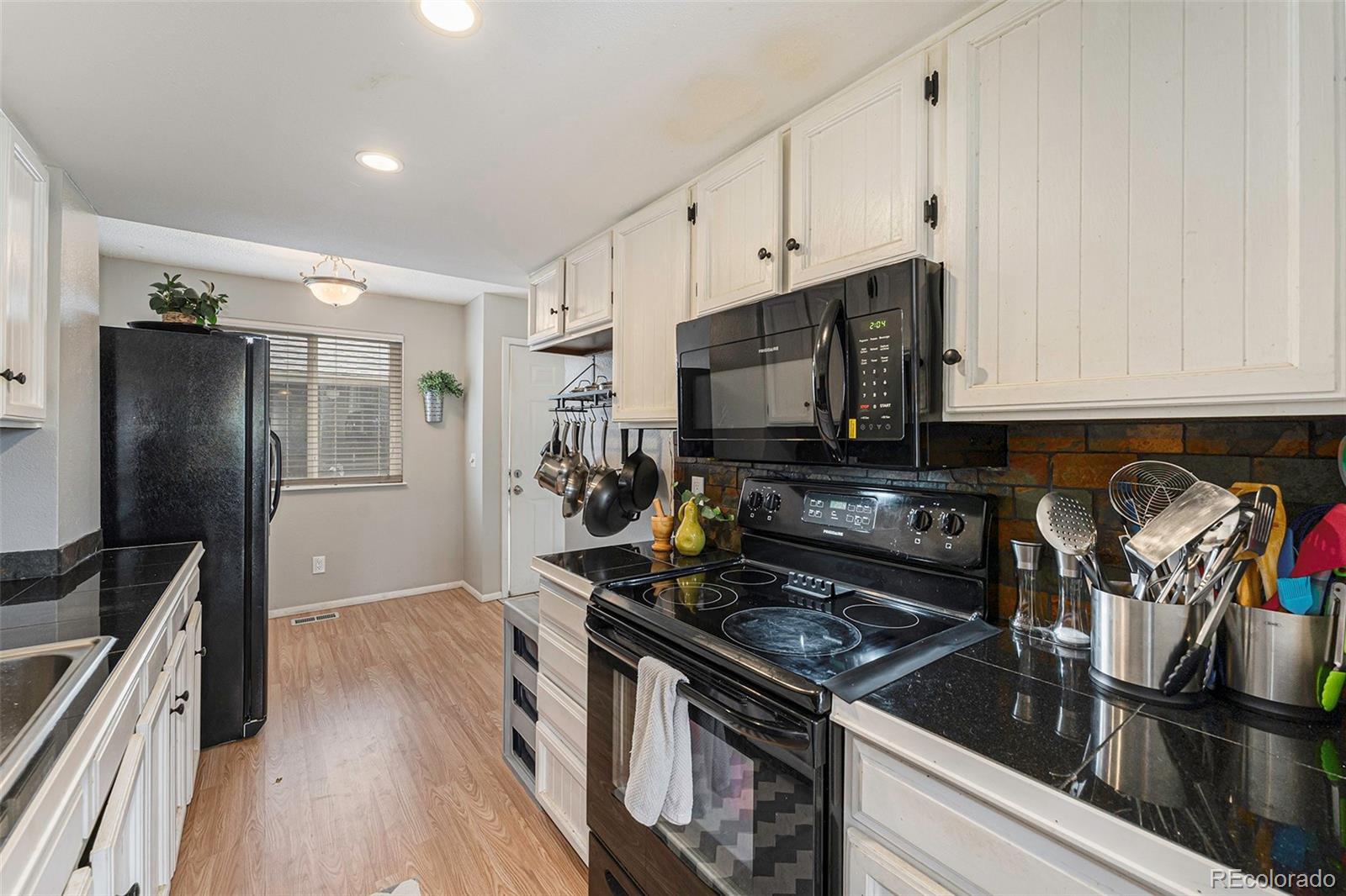 8642 Carr Loop Arvada, CO 80005 - Photo 10 of 22 a kitchen with stainless steel appliances granite countertop a stove refrigerator and microwave