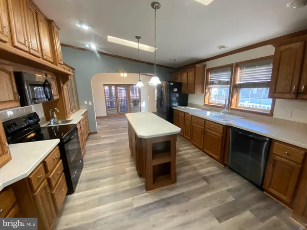 a large kitchen with stainless steel appliances wooden floor a stove and a sink