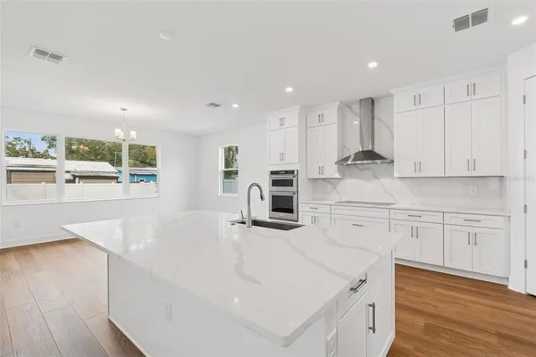 a large kitchen with stainless steel appliances lot of white cabinets and wooden floor