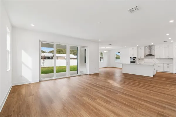 an open kitchen with white cabinets and wooden floor