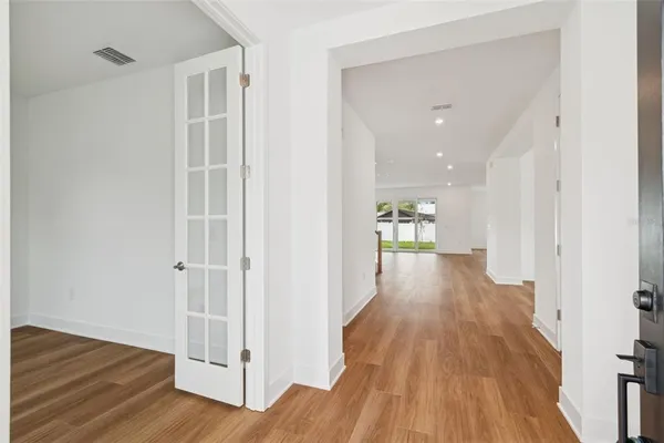 a view of a hallway with wooden floor and a bathroom