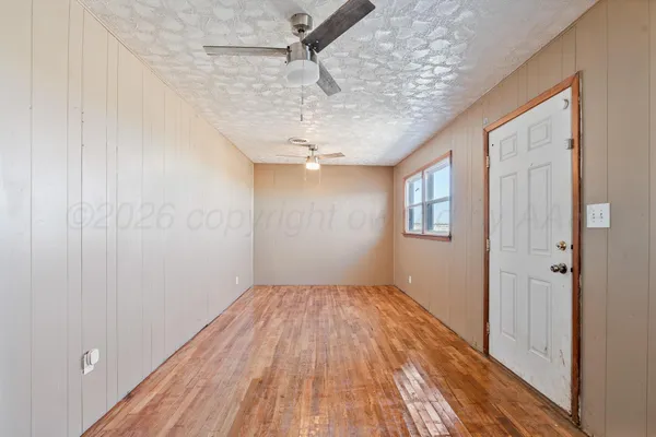a view of a room with wooden floor a ceiling fan and window