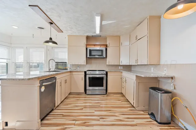a kitchen with granite countertop a stove top oven sink and cabinets