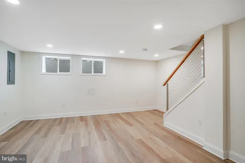a view of an empty room with wooden floor and stairs