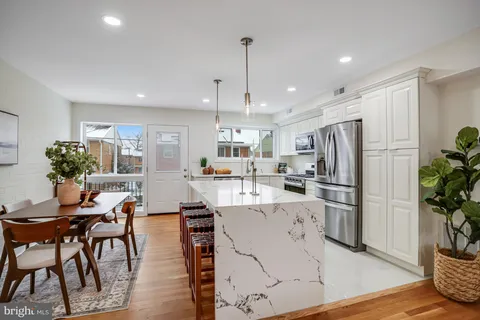 a kitchen with stainless steel appliances kitchen island granite countertop a refrigerator and a dining table