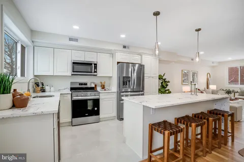 a kitchen with kitchen island granite countertop a sink stove and refrigerator