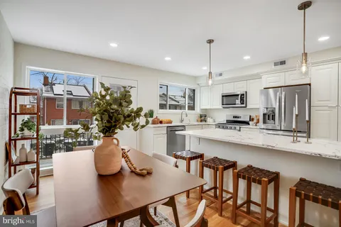 a kitchen with stainless steel appliances granite countertop a dining table chairs and stove