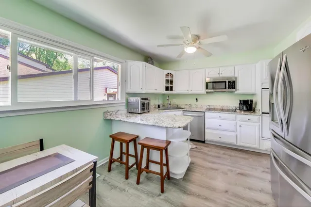 a kitchen with kitchen island granite countertop a sink appliances cabinets and a counter top space