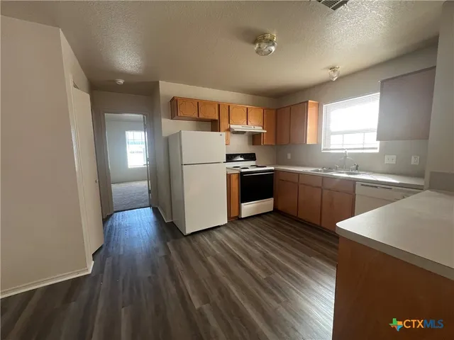 a kitchen with wooden floors and white stainless steel appliances