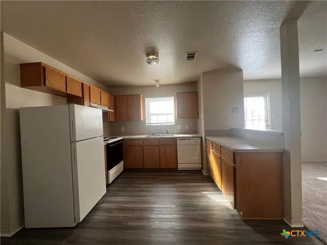 a kitchen with granite countertop a refrigerator and a sink