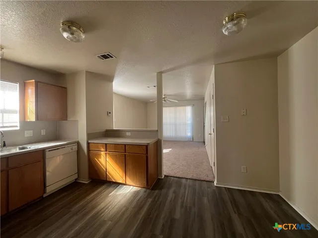 a view of a kitchen with a sink dishwasher and wooden floor