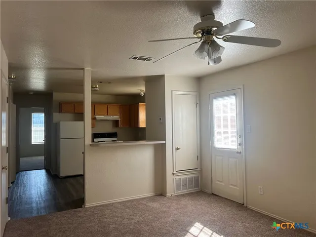 a view of a hallway with wooden floor and a kitchen