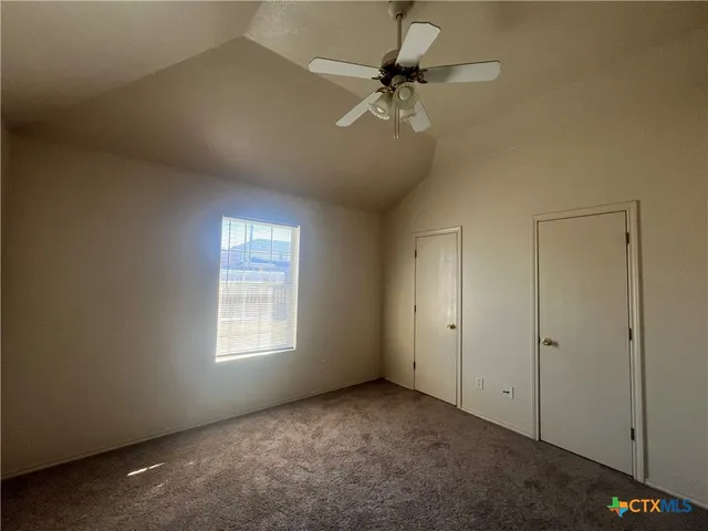 an empty room with windows and fan