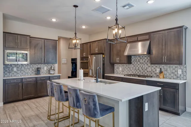 a kitchen with stainless steel appliances kitchen island granite countertop a sink a stove a refrigerator cabinets and chairs