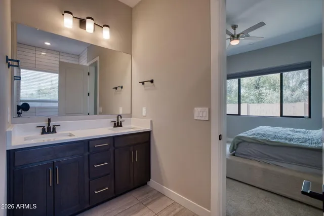 a en suite bathroom with a double vanity sink a large mirror and a bathtub