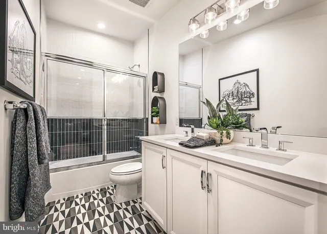 a bathroom with a sink a toilet a mirror and shower