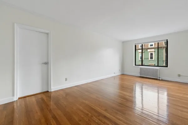 an empty room with wooden floor cabinet and windows