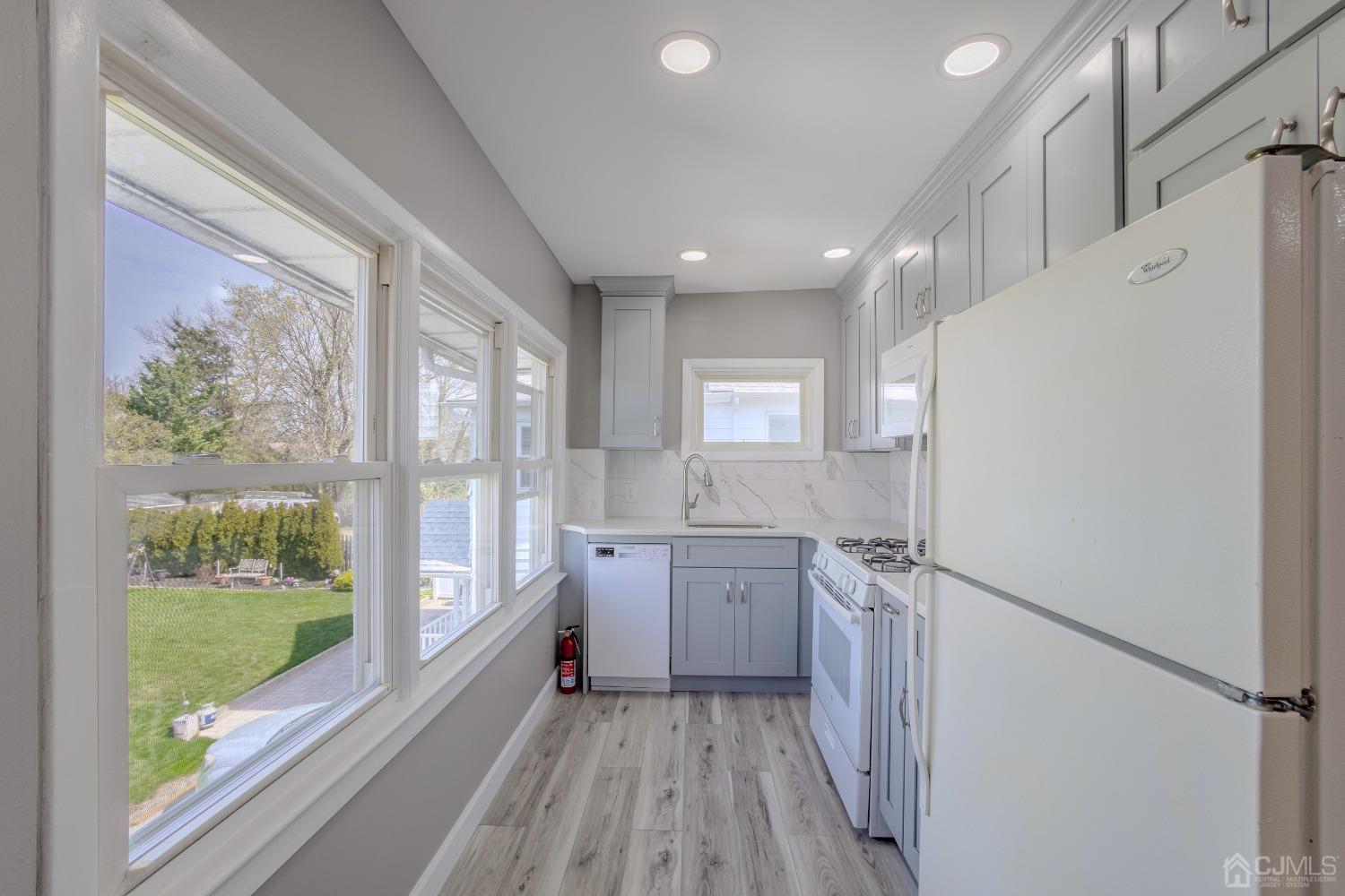 49 Riva Avenue, Unit 2 Milltown, NJ 08850 - Photo 14 of 22 a kitchen with granite countertop a refrigerator a sink a stove and white cabinets with wooden floor