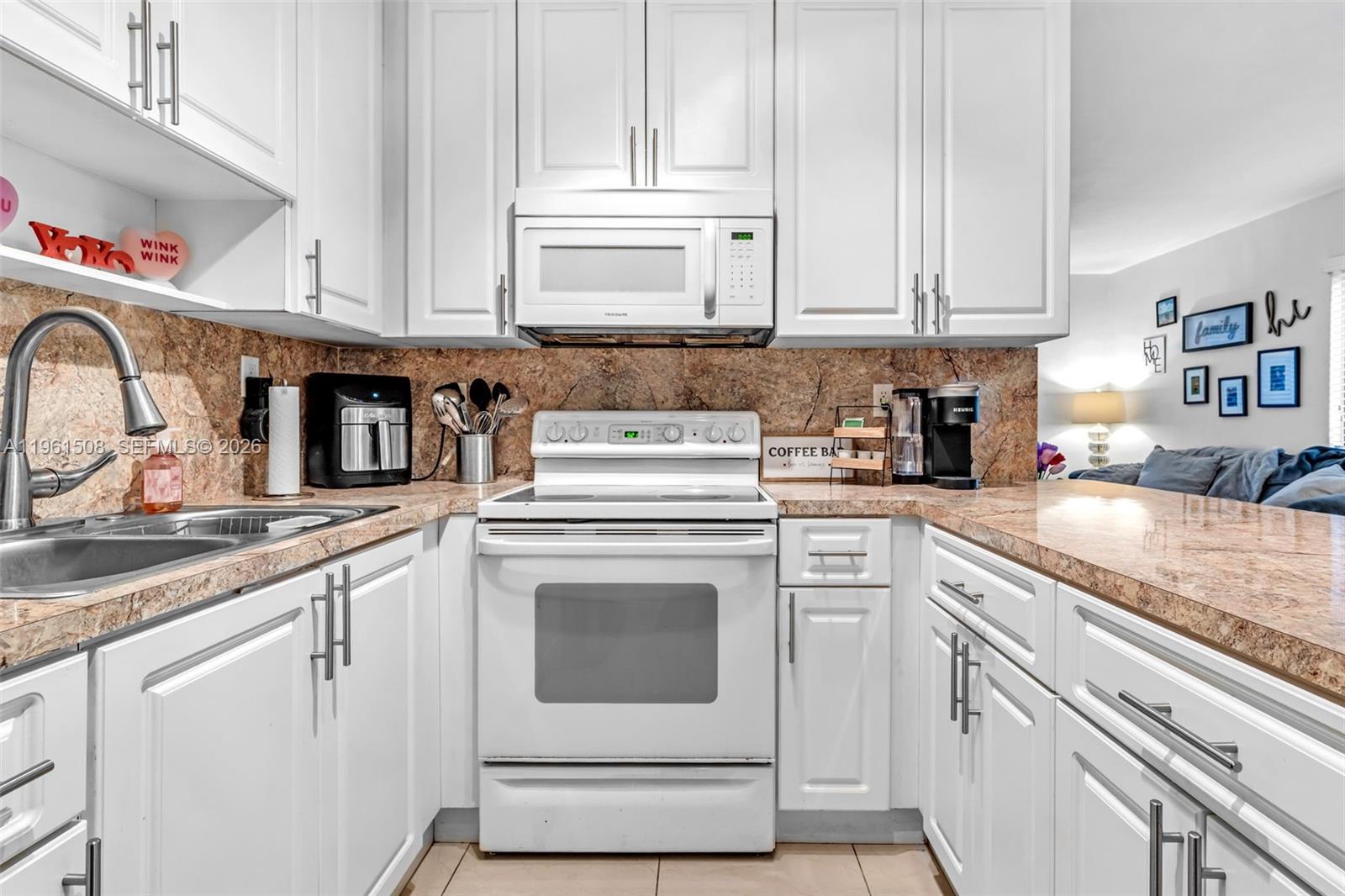 7585 Southwest 28th Street Miami, FL 33155 - Photo 10 of 28 a kitchen with granite countertop white cabinets and white appliances