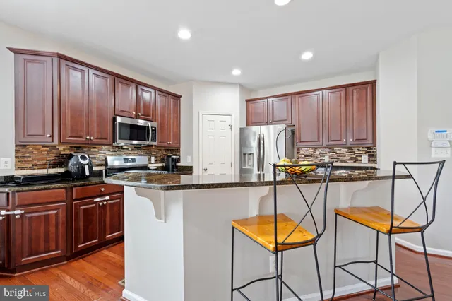 a kitchen with stainless steel appliances granite countertop wooden cabinets stove top oven and granite counter space