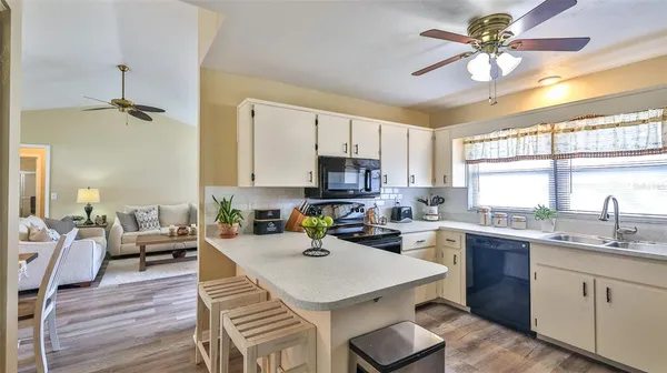 a kitchen with a sink a stove cabinets and living room view