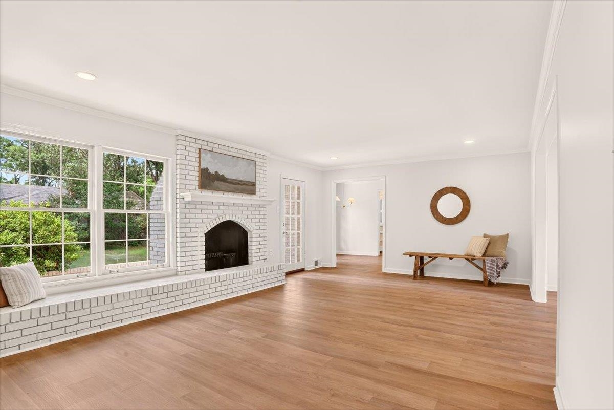 7674 Apple Valley Road Germantown, TN 38138 - Photo 5 of 15 Spacious living area featuring light wood-finish flooring, a white brick fireplace with mantel, and large multi-pane windows with a deep sill