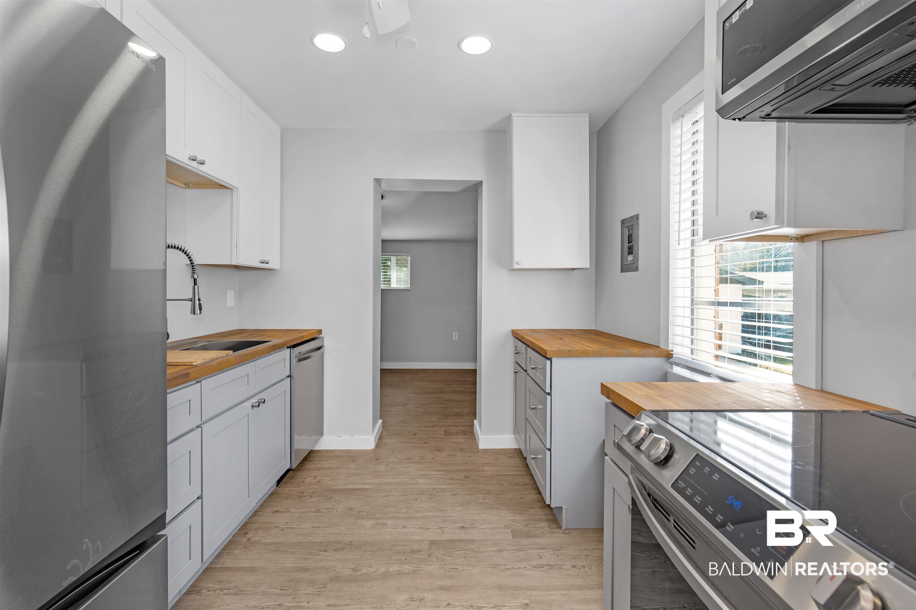 3005 Club House Road Mobile, AL 36605 - Photo 5 of 20 Kitchen featuring appliances with stainless steel finishes, sink, light hardwood / wood-style flooring, wooden counters, and white cabinets