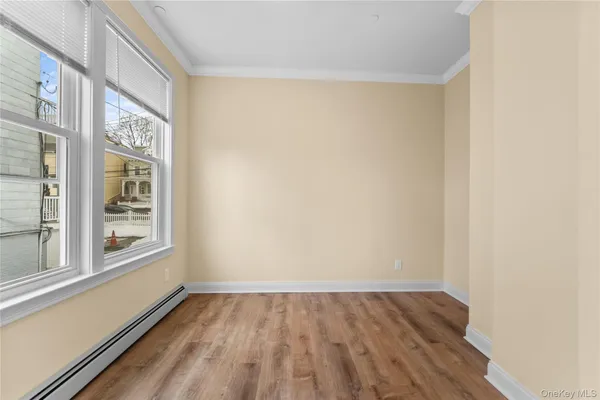 a view of an empty room with a window and wooden floor